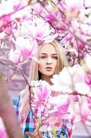 Glamour portrait of sexy young woman in blooming pink flowers photo
