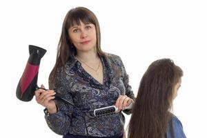 studio portrait of mother makes a hairstyle to her little daughter photo