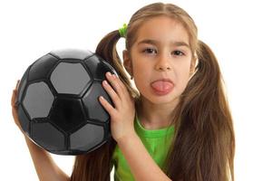 close-up portrait of a little girl who holds the ball and shows language photo