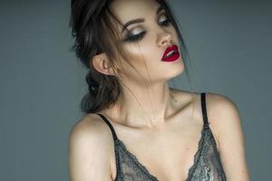 close up of beautiful young girl with sexy red lips and makeup posing in lace bra photo