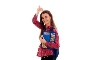 Happy stylish smart student girl with backpack on her shoulders and folders for notebooks in hands showing thumbs up and smiling on camera isolated on white background photo