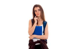 retrato de una joven estudiante pensativa con mochila azul y carpetas para cuadernos aisladas de fondo blanco foto