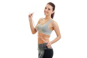 Cheerful brunette sports woman measure her waist and smiling on camera photo