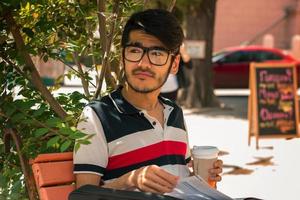 handsome guy in glasses who sits in the Park and drink coffee photo