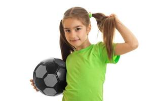 portrait of young girl in green shirt with soccer ball in hands photo