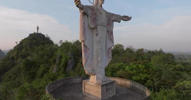 una vista aérea de cristo redentor en la montaña se destaca prominentemente en hup pha sawan en ratchaburi cerca de bangkok, tailandia video