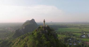 eine luftaufnahme von buddha auf dem berg steht prominent in hup pha sawan in ratchaburi in der nähe von bangkok, thailand video