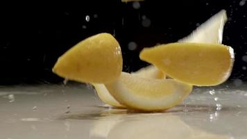 Fresh sliced lemon falling and splashing on water at slow motion video