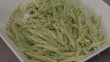 Pouring parmesan parmigiano on traditional Trofie Al Pesto typical pasta Liguria gourmet. Home homemade restaurant cuisine Mediterranean healthy food video