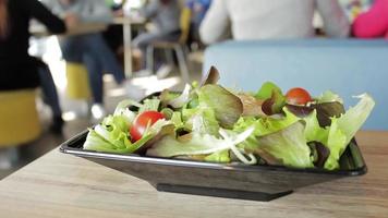 deliciosa salada com tomate pronto para ser comido em um restaurante. as pessoas estão comendo fora de foco no bar ao fundo. comida de saúde para dieta. conceitos vegetarianos ou veganos. video