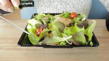 femme faisant la moue d'huile d'olive dans la salade. nourriture végétalienne biologique végétarienne. alimentation saine. restauration rapide à emporter. manger au restaurant.