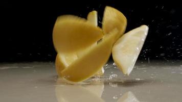 Fresh sliced lemon falling and splashing on water at slow motion video