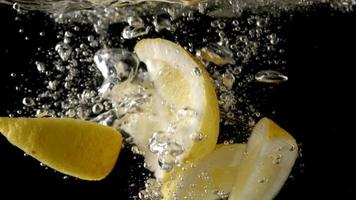 Sliced lemons fruit splashing in water video