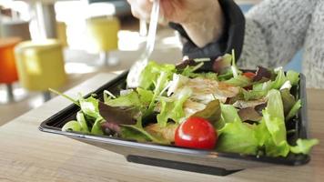 mulher comendo uma deliciosa salada com tomate em um restaurante. as pessoas estão comendo fora de foco no bar ao fundo. comida saudável para dieta. conceitos vegetarianos ou veganos. video