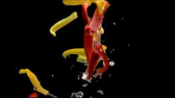 frische Paprika springen auf schwarzem Hintergrund. Bio-veganes vegetarisches Slice-Food, gesundes mediterranes Diätgemüse. Alphakanal Zeitlupe video