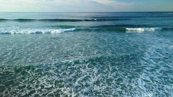 surfear olas con agua turquesa en praia de caion en galicia, españa. toma amplia aerea video