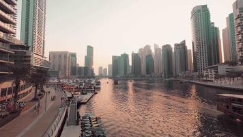 dubai, emiratos árabes unidos, 2022 - horizonte del puerto deportivo de dubai con barcos y rascacielos al atardecer. edificios y barcos en movimiento en el agua capturados desde el centro comercial marina, dubai, emiratos árabes unidos. video