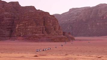 Wadi rum desert landscape with line of 4wd vehicles drive from sunset viewpoint on organized sunset tour in Jordan