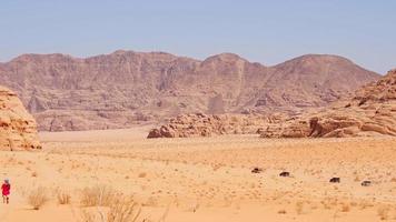 paysage désertique du wadi rum avec trekking touristique et ligne de véhicules 4x4 sur la route sablonneuse du désert de la vallée lors d'un safari organisé en jordanie video