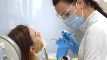 dentista en unform trata los dientes de las niñas en la clínica