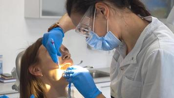 dentista em forma trata dentes de meninas na clínica video