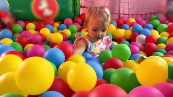 Cheerful little toddler girl plays with multicolor balls in childrens pool video