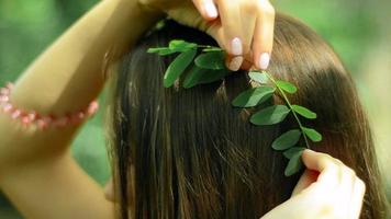 young brunette inserts in leaves into the hair in the forest