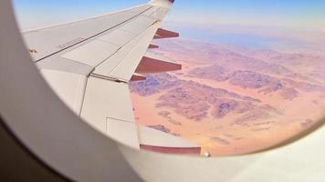 vista de la ventana del avión con hermosas texturas y paisaje del desierto de wadi rum en jordania medio oriente. concepto de viaje y transporte aéreo. visita viajar al concepto de jordania video