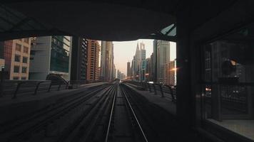 Dubai, UAE, 2022 - metro train on railway in Dubai with museum of future and sunset sky background with skyline panorama