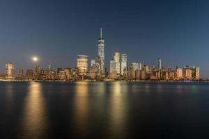 horizonte de nueva york visto a través del río hudson en nueva jersey al atardecer con la superluna en el fondo. foto