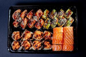 Traditional delicious fresh sushi roll set on a black background with reflection. Sushi roll with rice, cream cheese, avocado, salmon, sesame. Philadelphia. Sushi menu. Japanese kitchen, photo