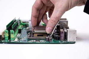 Engineer repairman holding hands in black gloves chip processor, CPU to insert into the socket of the computer motherboard. The concept of technology hardware in the neon light photo