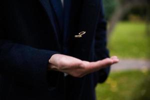 Groom holding wedding rings in hand. Two wedding rings on the floor with contrast wedding rings on floor, on ground, on piano, in hand photo