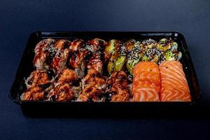 Traditional delicious fresh sushi roll set on a black background with reflection. Sushi roll with rice, cream cheese, avocado, salmon, sesame. Philadelphia. Sushi menu. Japanese kitchen, photo