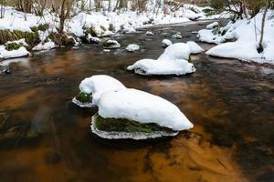 un pequeño río de bosque rocoso en invierno foto