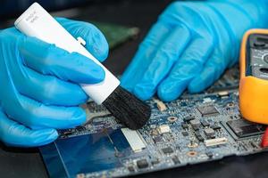 Technician use brush and air blower ball to clean dust in circuit board computer. Repair upgrade and maintenance technology. photo