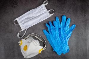 Protective medical mask, respirator and gloves on black background. Protective equipment against pollution, virus, flu and coronavirus, covid 19. photo