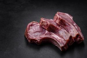 Fresh raw pork meat on the ribs with spices and herbs on a wooden cutting board photo