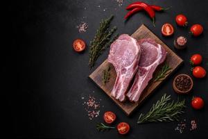 Fresh raw pork meat on the ribs with spices and herbs on a wooden cutting board photo