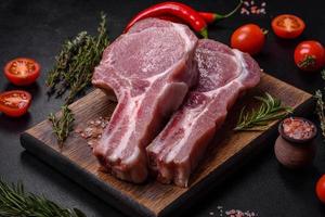 carne de cerdo cruda fresca en las costillas con especias y hierbas en una tabla de cortar de madera foto