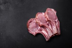 Fresh raw pork meat on the ribs with spices and herbs on a wooden cutting board photo