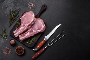 Fresh raw pork meat on the ribs with spices and herbs on a wooden cutting board photo
