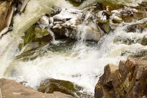 Mountain river in a beautiful winter green coniferous forest on the slopes of the mountains photo