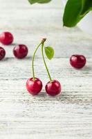 dos cerezas rojas con hojas en un fondo blanco foto