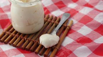 Fresh yogurt in a plastic container and spoon on table video