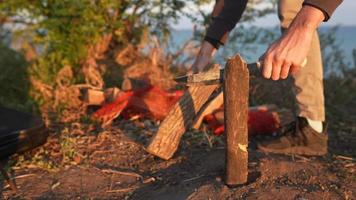 preparando leña en un camping con un cuchillo y un registro video