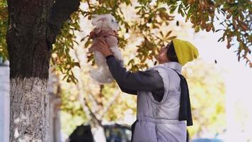 Woman holds and tosses little white dog in the air video