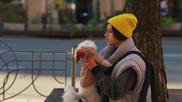 Woman holds and talks to little white dog video