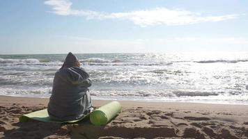 Person seated on a beach watching the waves video