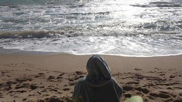 Person, die an einem Strand sitzt und die Wellen beobachtet video